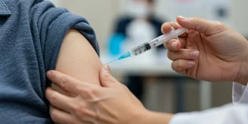 Profissional de saúde aplicando vacina contra a gripe em idoso, simbolizando a campanha nacional de imunização.